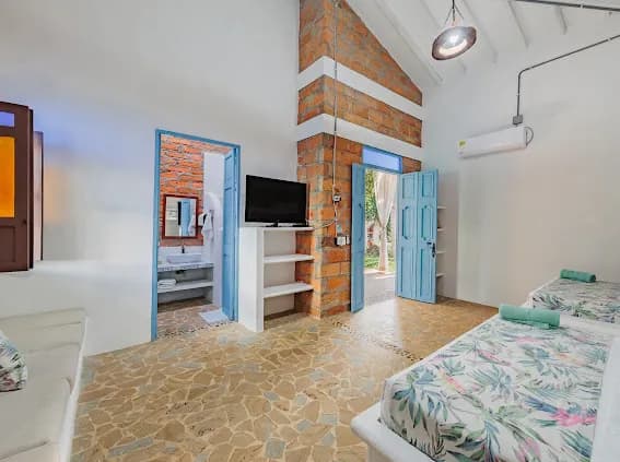 Habitacion con TV, columna de ladrillo y bano privado